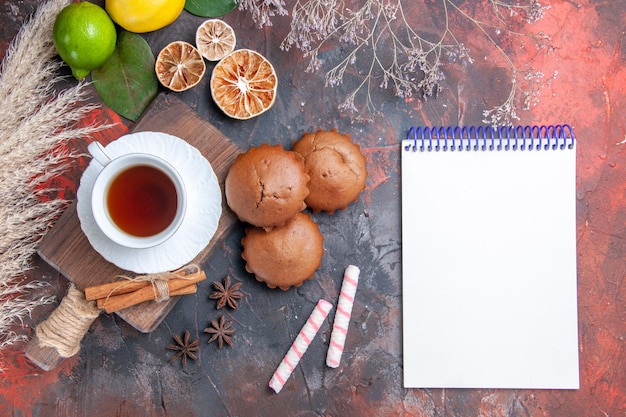 Top view a cup of tea lime lemon cinnamon a cup of black tea on the board white notebook