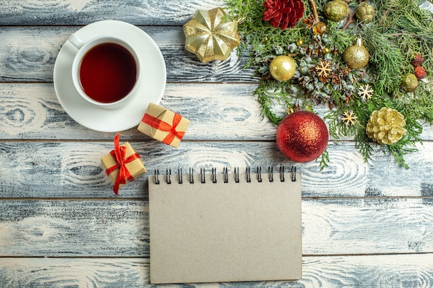 Top view a cup of tea a notebook gifts fir tree branches on wooden background