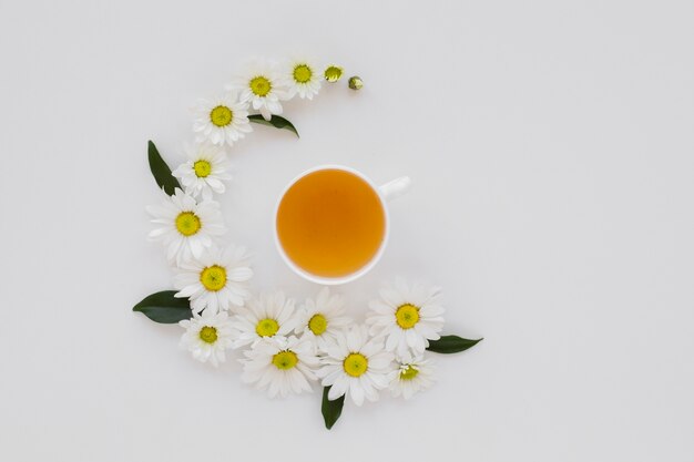 Top view cup of tea surrounded by flowers