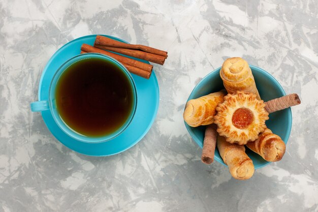 Vista dall'alto tazza di tè con bagel e cannella sulla superficie bianca