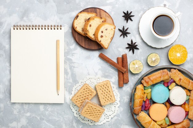 Top view cup of tea with bagels and macarons on white