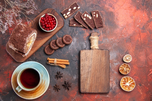 Top view of cup of tea with biscuit roll on dark surface