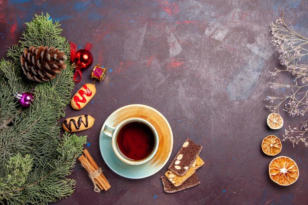 Top view cup of tea with biscuits on a dark space