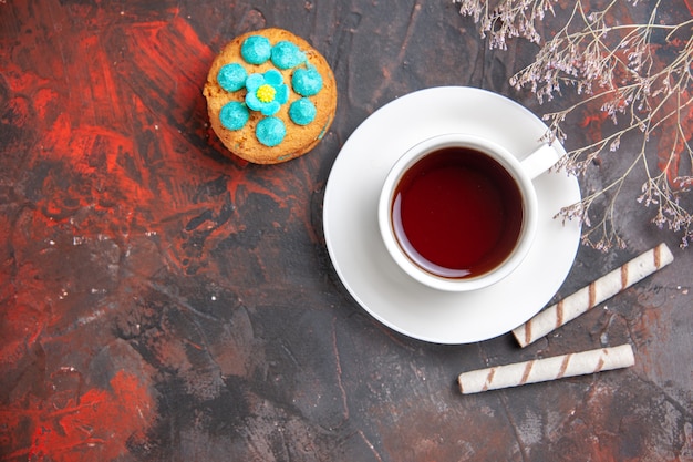 Foto gratuita vista dall'alto tazza di tè con biscotti sul tavolo scuro