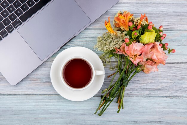 灰色の木に素晴らしい花の花束とお茶のカップのトップビュー