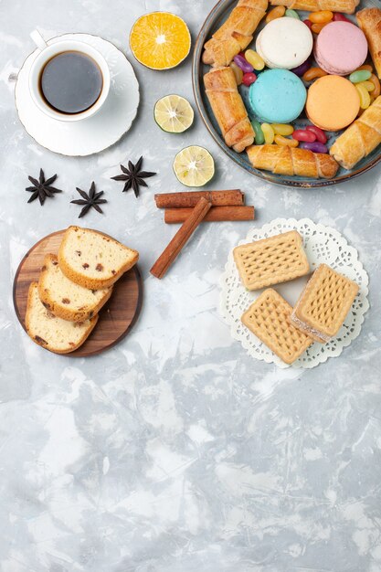 Top view cup of tea with cake slices and bagels on white