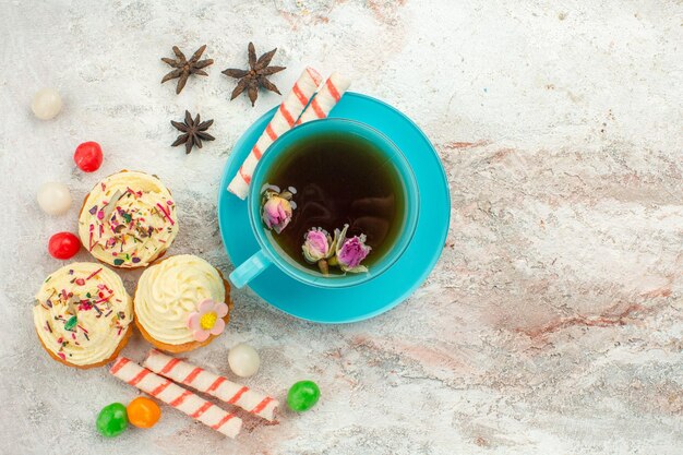 Top view cup of tea with candies and cakes on white surface tea dessert biscuit cake pie