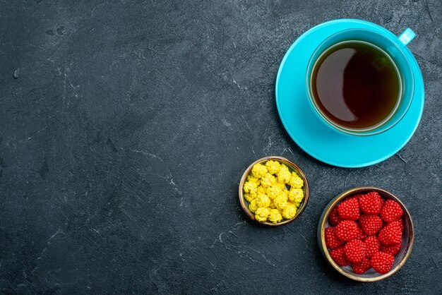 Top view cup of tea with candies on grey desk candy sugar sweet tea