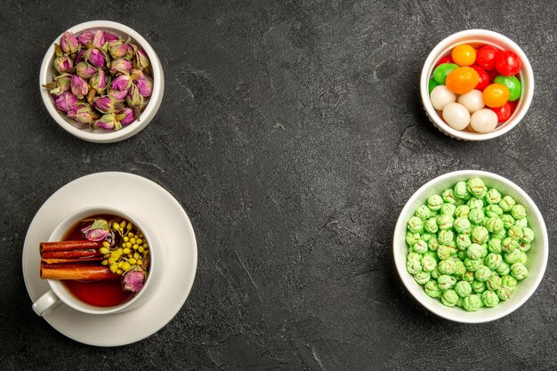 Top view cup of tea with candies on grey desk tea color rainbow flavor