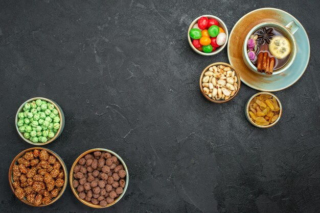 Top view cup of tea with candies on grey space