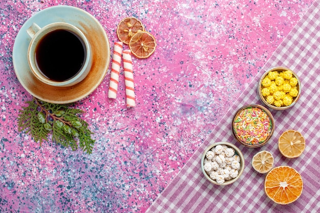 ピンクの机の上にキャンディーとお茶のトップビューカップキャンディーティードリンク甘い砂糖コンフィチュールカラー