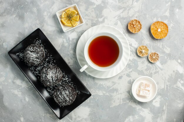 明るい白い机の上にチョコレートケーキとお茶のトップビューカップ