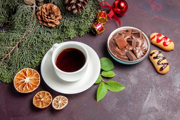 Top view cup of tea with chocolate dessert and biscuits on dark space