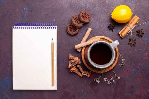 Top view cup of tea with cinnamon cookies and lemon on dark background tea sweet color photo