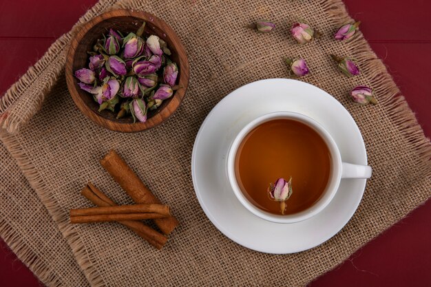 トップビューベージュのナプキンにシナモンと乾燥したバラのつぼみとお茶のカップ