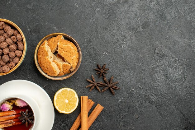 Top view cup of tea with cinnamon and flakes on a dark-grey surface tea drink ceremony sweet