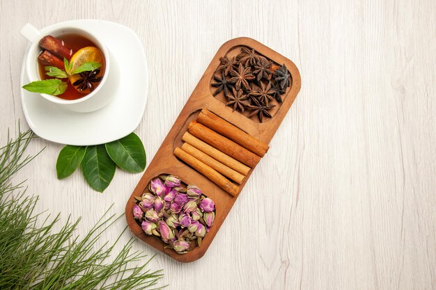 Top view cup of tea with cinnamon and flowers on white desk tea color flavor flower