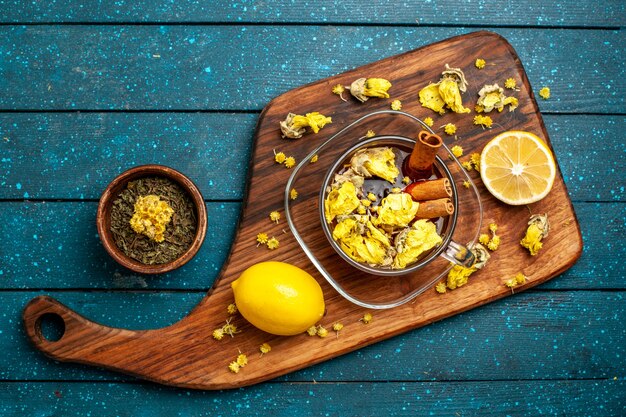 Top view cup of tea with cinnamon and lemon on blue desk