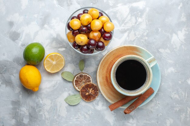 Вид сверху чашка чая с корицей, лимоном и вишней на белой поверхности пить чай корицы лимонного цвета