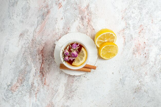 Top view cup of tea with cinnamon and lemon slices on a white space