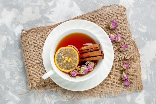 Top view cup of tea with cinnamon and lemon on white desk