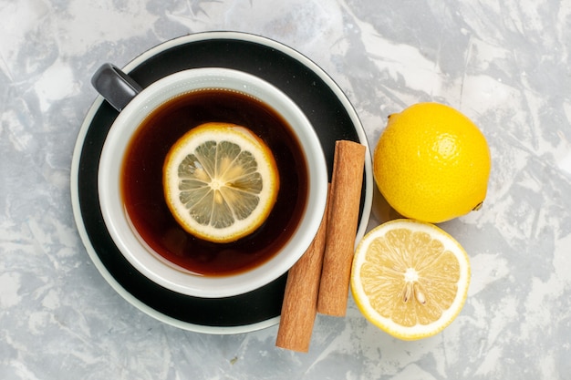 Free photo top view cup of tea with cinnamon and lemon on the white surface