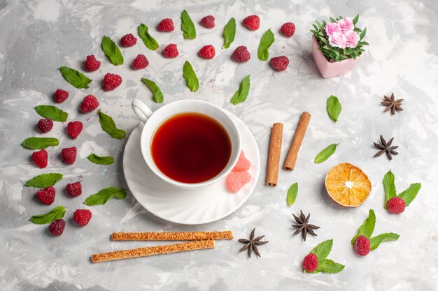 Top view cup of tea with cinnamon and raspberries on white surface tea berry fruit cinnamon