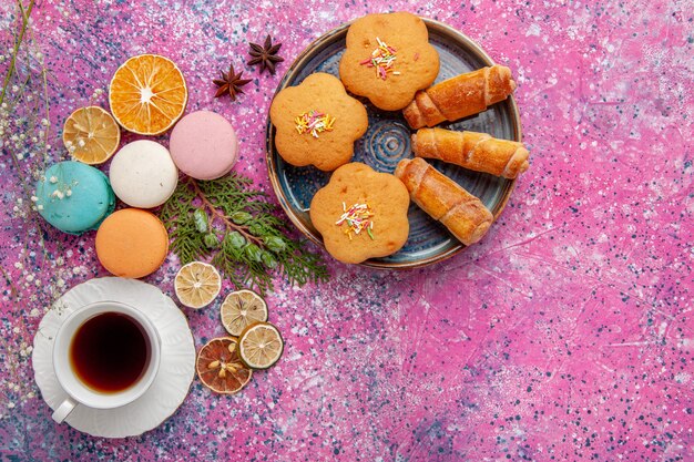 Top view cup of tea with colorful french macarons and bagels on the light pink wall cake biscuit sugar sweet pie tea cookie