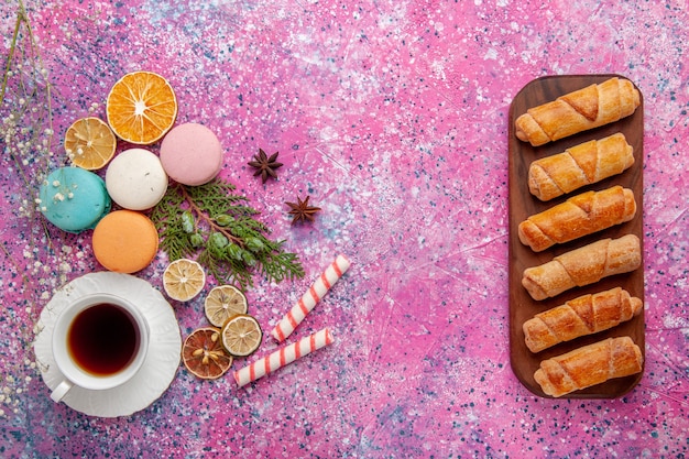 Vista dall'alto tazza di tè con colorati macarons francesi e ciambelle sulla scrivania rosa torta biscotto zucchero torta dolce tè biscotto