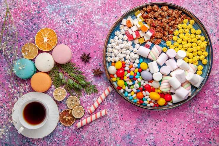 Free Photo top view cup of tea with colorful french macarons on pink surface