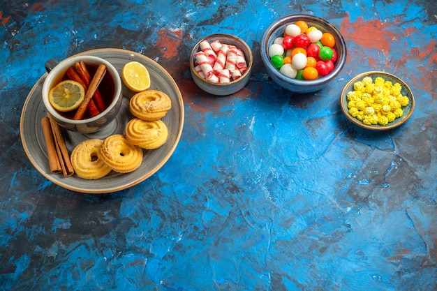 Top view cup of tea with cookies and candies on blue table biscuit candy tea