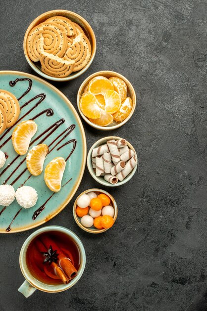 Top view cup of tea with cookies and candies on dark grey table cookie cake biscuit tea