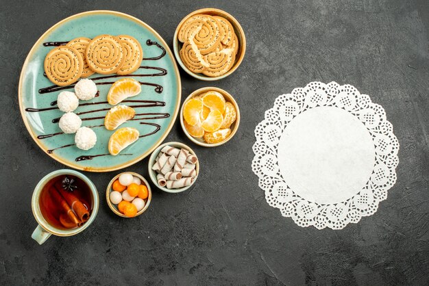 Top view cup of tea with cookies and candies on the grey table cookie cake biscuit tea