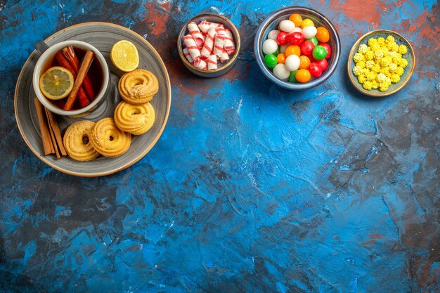 Top view cup of tea with cookies and candies on light blue table biscuit candy tea