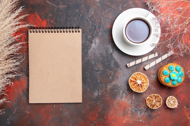 Top view cup of tea with cookies on dark floor