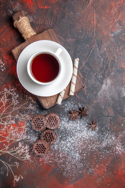 Top view cup of tea with cookies on a dark table