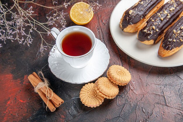 Top view cup of tea with cookies and eclairs on dark floor sugar tea biscuit sweet