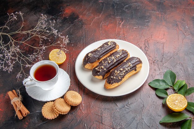 Top view cup of tea with cookies and eclairs on dark table sugar tea biscuit sweet