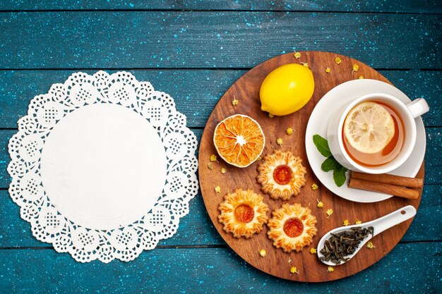 Top view cup of tea with cookies and lemon on blue desk