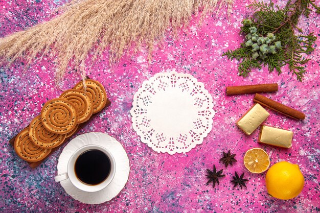 Top view cup of tea with cookies lemon and cinnamon on light pink desk.