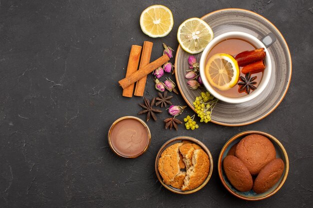 Top view cup of tea with cookies and lemon slices on dark surface tea sugar fruit biscuit sweet cookie