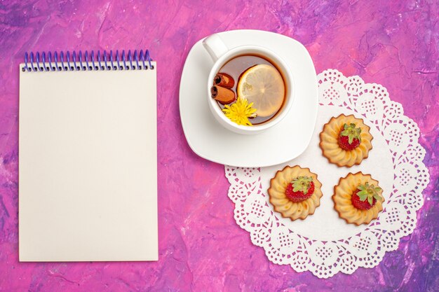 Top view cup of tea with cookies on the pink table candy color tea biscuit