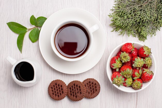 Top view cup of tea with cookies and strawberries on white desk sugar tea cookies biscuit sweet