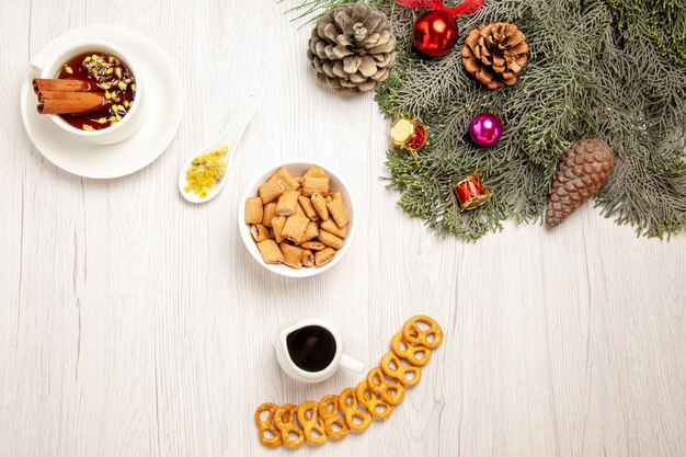 Top view cup of tea with cookies and tree on white space