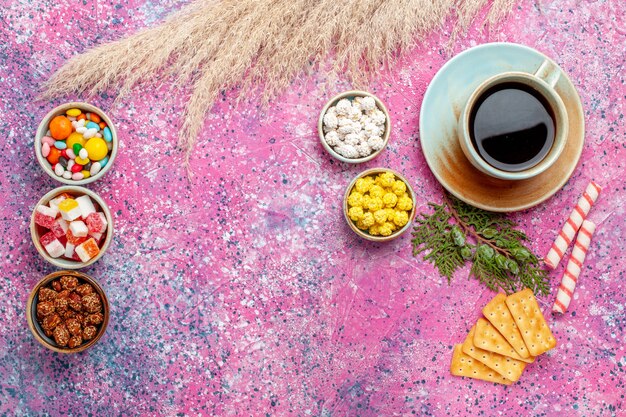 Top view cup of tea with crackers and candies on the pink desk