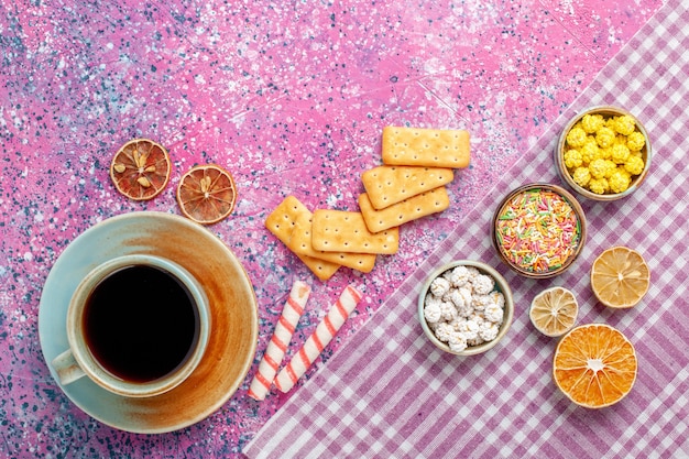 Top view cup of tea with crackers and candies on the pink desk