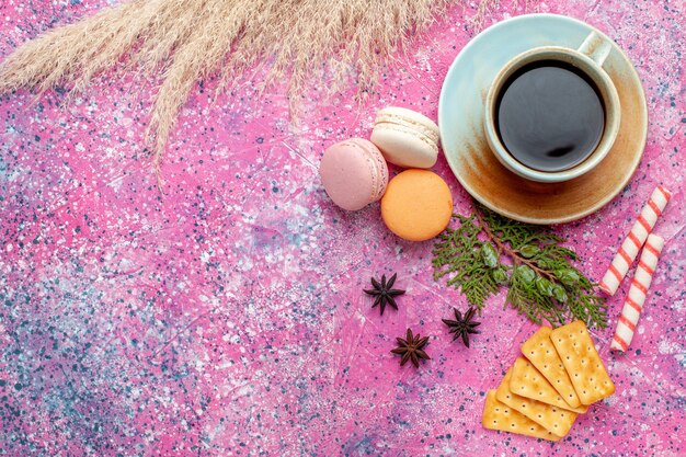 Top view cup of tea with crackers and macarons on pink surface