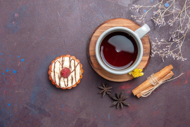 Top view cup of tea with delicious cake on dark background tea cake sweet pie cookie biscuit