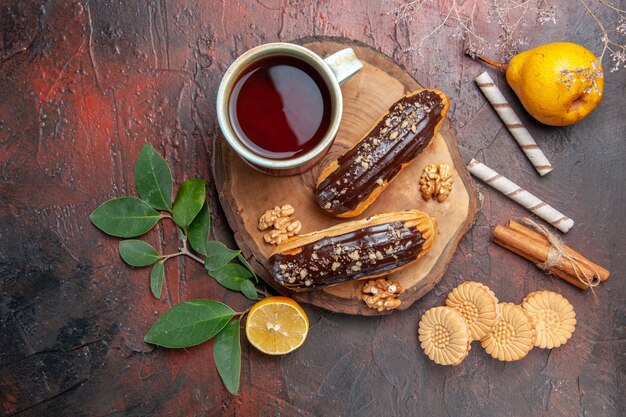 어두운 테이블 케이크 달콤한 디저트에 맛있는 초코 eclairs와 차의 상위 뷰 컵