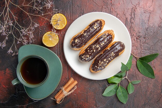 어두운 테이블 설탕 비스킷 디저트 달콤한에 맛있는 eclairs와 차의 상위 뷰 컵